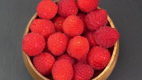 Ripe raspberries close up rotate in a wooden bowl. Juicy fresh raspberry berry is healthy