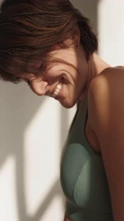 Femme adulte sportive souriant par la fenêtre à la lumière naturelle