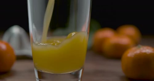 Fresh Orange Juice Pouring into Glass on Table