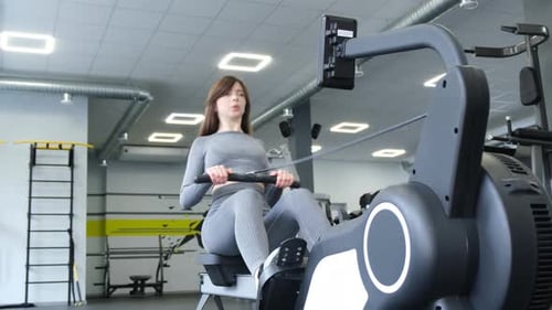 Female Athlete Trains on the Simulator Fitness Girl Works in the Gym