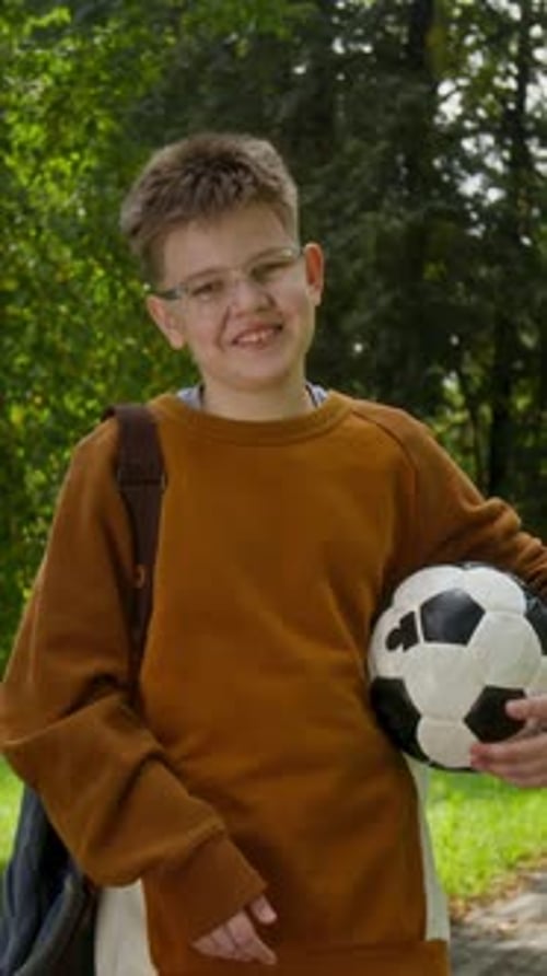 Smiling Teenager Holds Soccer Ball in Green Park