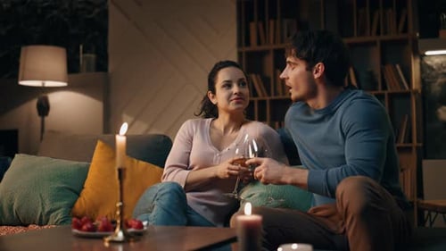 Loving Couple Drinking Wine Sitting Couch with Candles Romantic Evening at Home