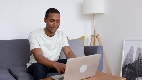 Man Working on Laptop While Sitting on Sofa