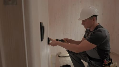 Electrician Installing Electrical Outlet in New Home Construction