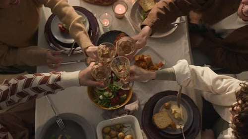 Top View of Festive Gathering of Friends Raising Toasts Over Table with Food