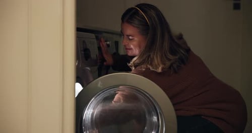 Woman Loading Clothes into Washing Machine at Home