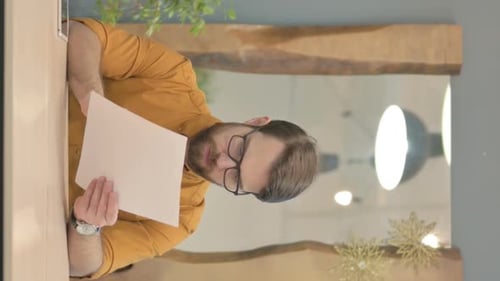 Vertical Video of Young Businessman Reading Documents in Office