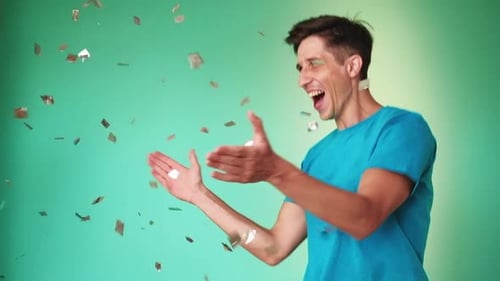 Man Celebrating with Confetti on Green Background