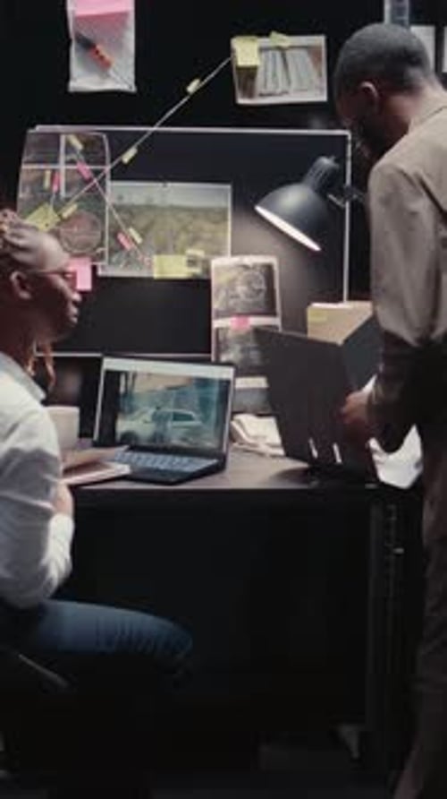 Detectives Collaborating on Case in Dimly Lit Office