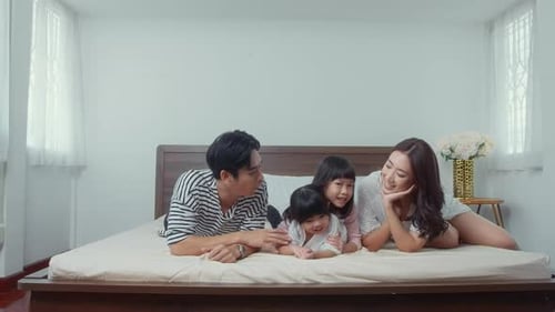 Happy Family Relaxing on Bed in Bright Bedroom