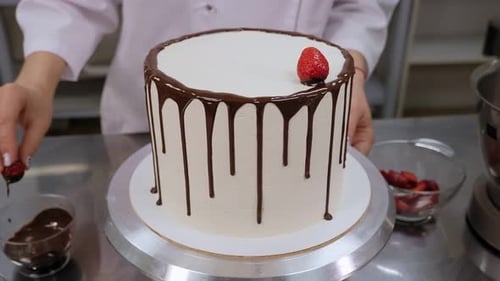 Woman Decorating Chocolate Drip Cake with Fresh Strawberries