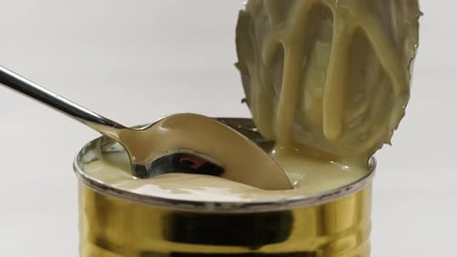 Sabrosa cuchara de leche condensada y gofres sobre mesa gris claro, espacio plano para texto