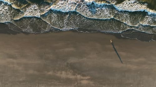Beautiful Cinematic Drone Shot of Couple Walking on The Beach During Sunset