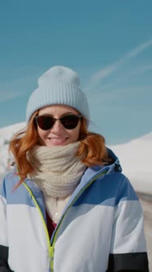Vertical Screen Portrait of female happily walking towards the snowy road.