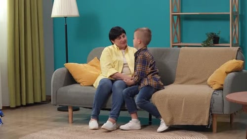 Close Up Shot of Woman Grandmother and Her Grandson Sitting on the Sofa in the Room Talking Smiling