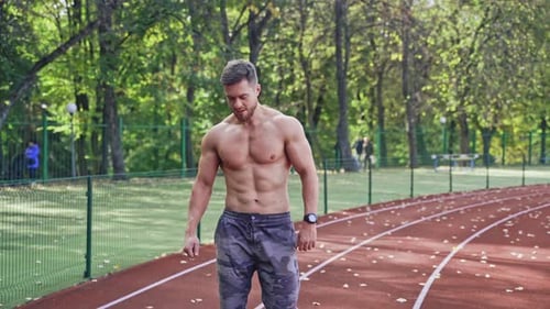 Fitness young man runs at outdoor stadium.