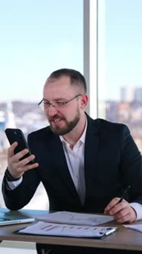 Corporate Man Working at Desk with Phone and Reports