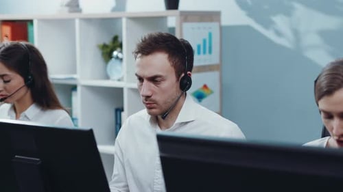 Mitarbeiter des technischen Supports mit Headset, der im Büro arbeitet und dann direkt zur Kamera schaut und