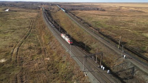 Electric Locomotive is Pulling a Freight Train Through the Autumn Countryside Aerial View