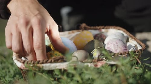 Panier tricoté avec des œufs de Pâques, dans l'herbe. Je prends et j'examine les œufs un par un. Gros plan.