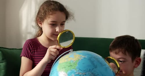 Children Studying Globe with Magnifying Glasses Indoors