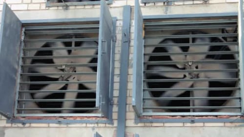 Industrial ventilation system with fans running behind bars