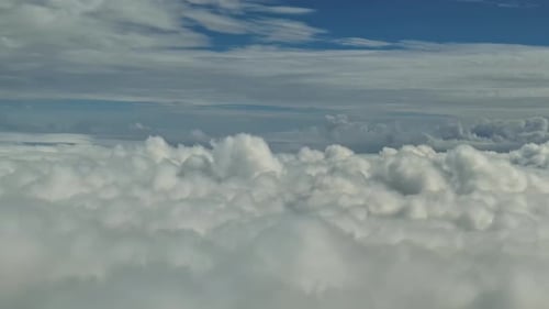 A Spectacular View from the Airplane Window with Clouds Passing By and Blue Skies.