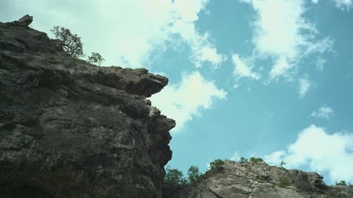 Looking up at the sky with moving clouds above the mountains, High cliffs and clouds