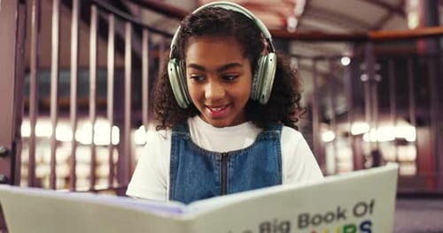 Happy, child and reading book with headphones, library and learning with fiction, knowledge or info
