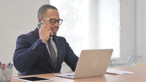 Man in Suit Talking on Phone at Desk