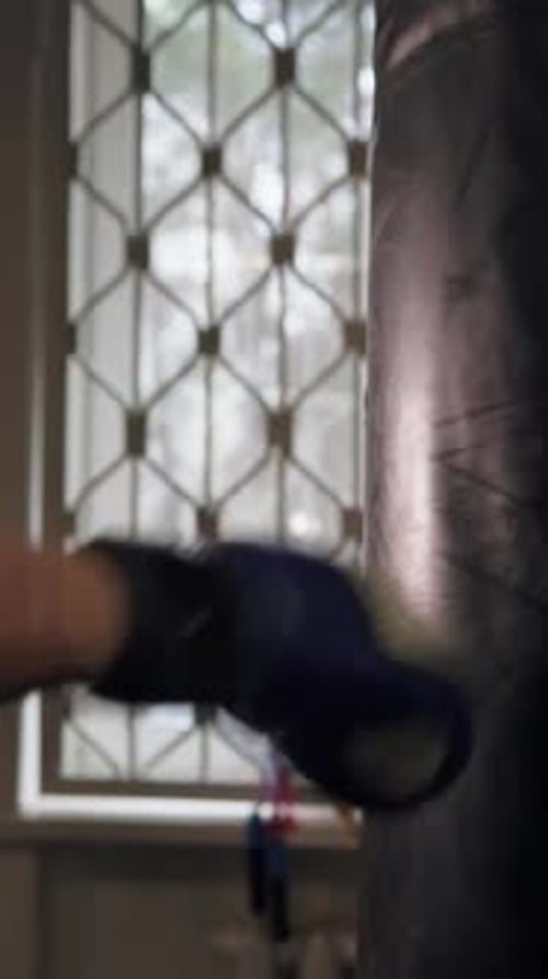 Close-up of a punch on a punching bag. Male fighter in boxing gloves trains in gym before fight.