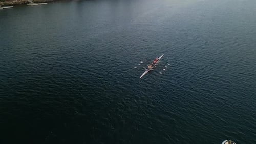 Drohnenaufnahme von oben auf ein Sportkanu mit einem jungen Athletenteam, das den Ozean trainiert