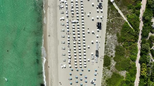 Top-down drone view over the white sand beaches and turquoise waters in front of One Hotel in Miami