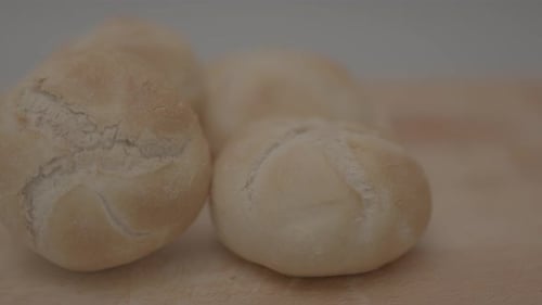 Slow motion pan of kaiser roll on a wooden plank