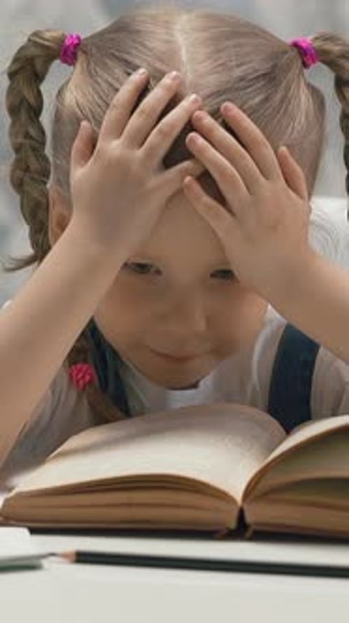 Cute Child with Plaits Tired of Doing Homework Sits at Table