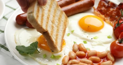 Toast Dipping into a Delicious Breakfast Plate