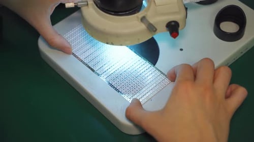 Ein Techniker in einem Labor kontrolliert die Qualität von LED-Dioden auf einem LED-Panel an einer modernen LED-Leuchte