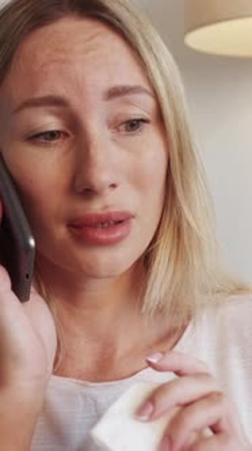 Woman Talking on Phone While Using Tissue