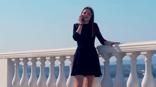media, communication - beautiful girl on a seaside terrace talking on cellphone