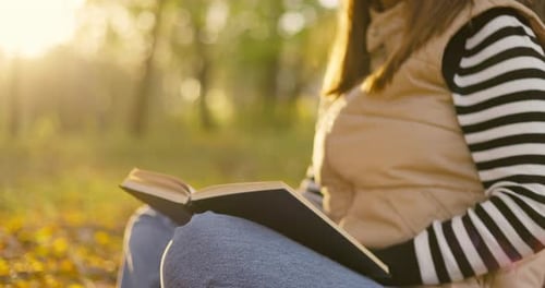 Young Woman Reading Book in Autumn Park