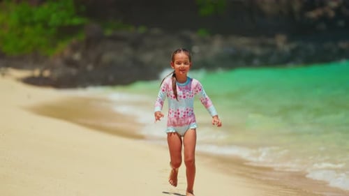 A Cute Little Girl is Happily Running Along the Ocean Shore with Beautiful Turquoise Water Happy