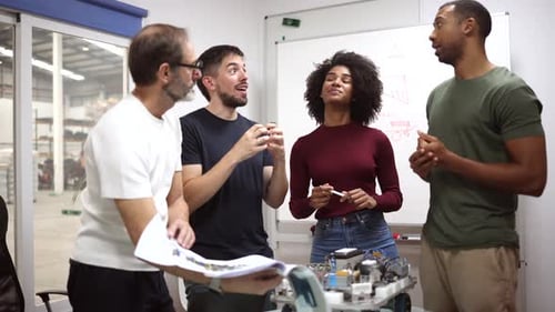 Multi generational and multiracial team of engineers working together on a robotics project in a mod