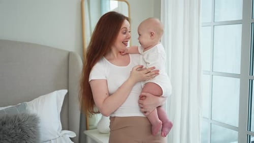 Mother Holds Her Infant in Bedroom