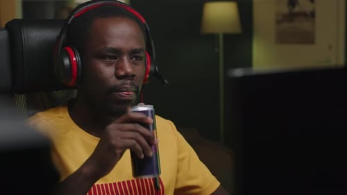 African American Male Gamer Drinking Energy Drink while Playing Games at Home