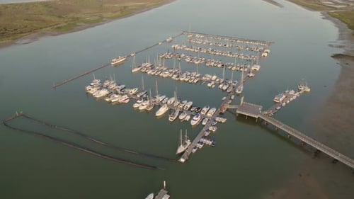 Marina at dawn during low tide. Dolly out of dock, pontoon and boats of different types. Aerial view