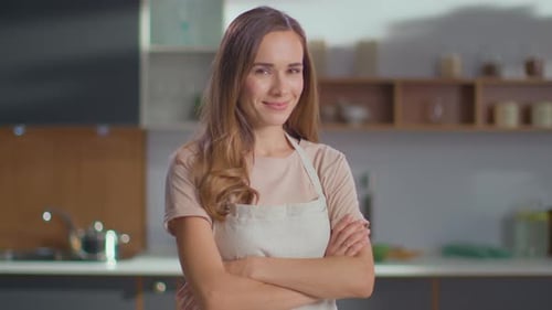 Woman in apron smiles in modern kitchen setting