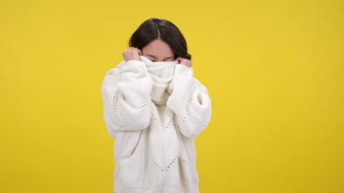 Linda jovem esconde o rosto atrás de um cachecol quente de forma divertida