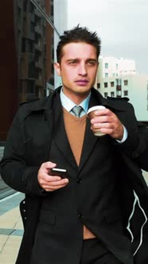 Man Drinks Coffee and Looks at Phone