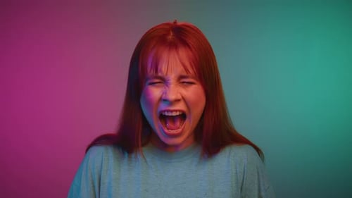 Portrait of Young Woman Looking at Camera and Screaming in Neon Lights of Studio