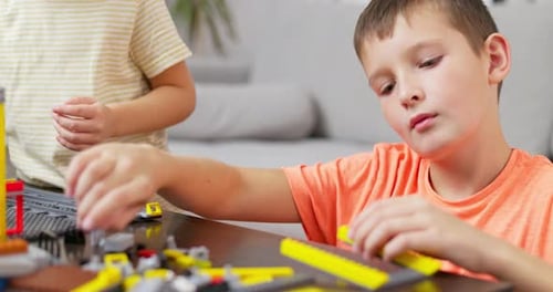 Two Children Playing and Building with Colorful Plastic Bricks at the Table